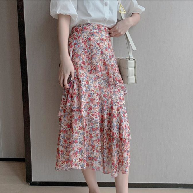 シフォンシャツ と 花柄のティアードスカートを着た女性