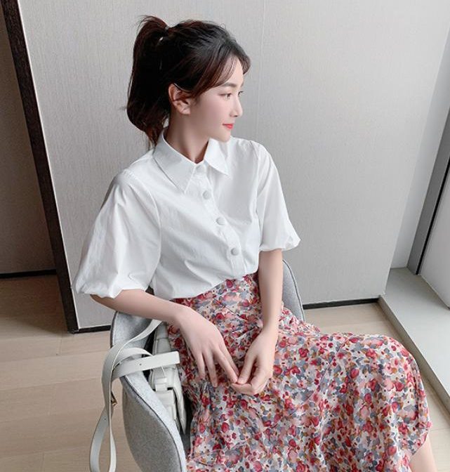 シフォンシャツ と 花柄のティアードスカートを着た女性