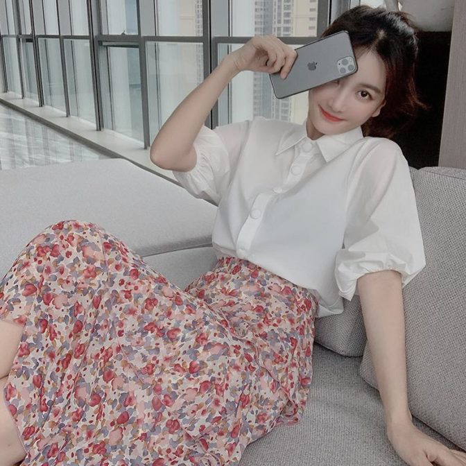 シフォンシャツ と 花柄のティアードスカートを着た女性