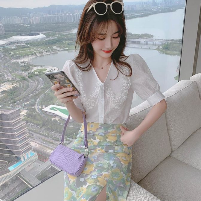 Vネックのシフォンシャツ と花柄のサマースカートを着た女性