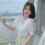 Vネックのシフォンシャツ と花柄のサマースカートを着た女性