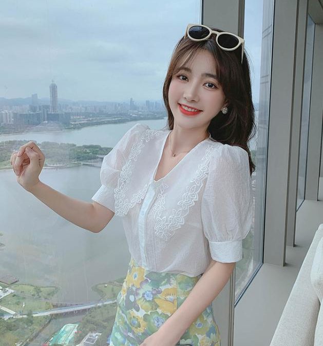 Vネックのシフォンシャツ と花柄のサマースカートを着た女性