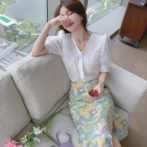 Vネックのシフォンシャツ と花柄のサマースカートを着た女性