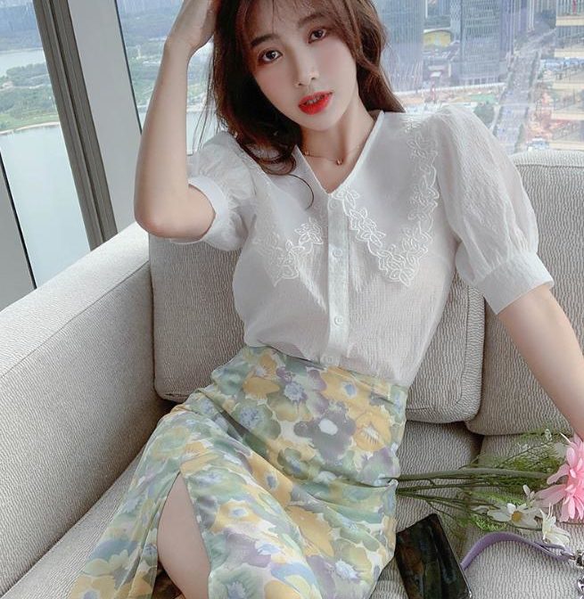 Vネックのシフォンシャツ と花柄のサマースカートを着た女性