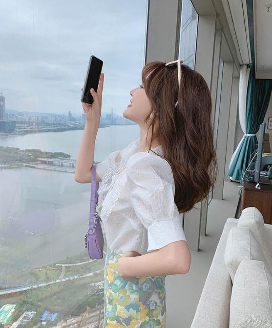 Vネックのシフォンシャツ と花柄のサマースカートを着た女性