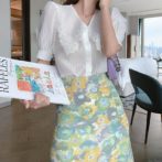 Vネックのシフォンシャツ と花柄のサマースカートを着た女性