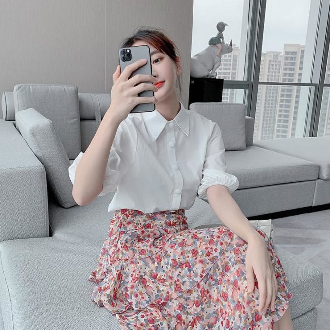 シフォンシャツ と 花柄のティアードスカートを着た女性