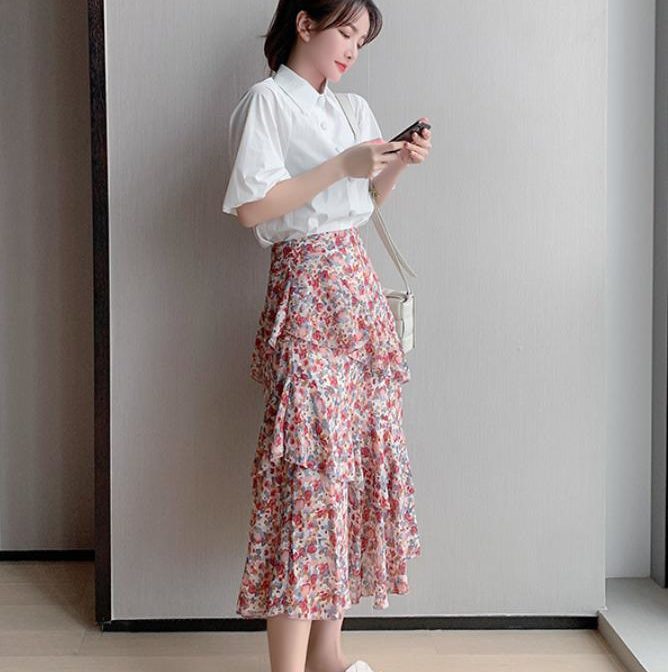 シフォンシャツ と 花柄のティアードスカートを着た女性